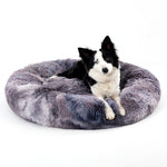 Dog lying on a fluffy gray pet bed against a white background