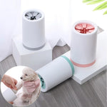 A pet grooming brush attachment set shown on a tabletop with two white cylindrical brush heads, one with a gray band and one with a pink band, plus an inset circle showing a small dog wearing a pink grooming brush.